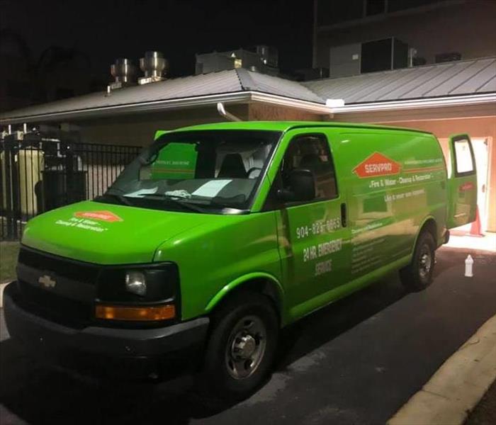 Image shows a green SERVPRO vehicle backed up to the doors of an assisted living facility at night.