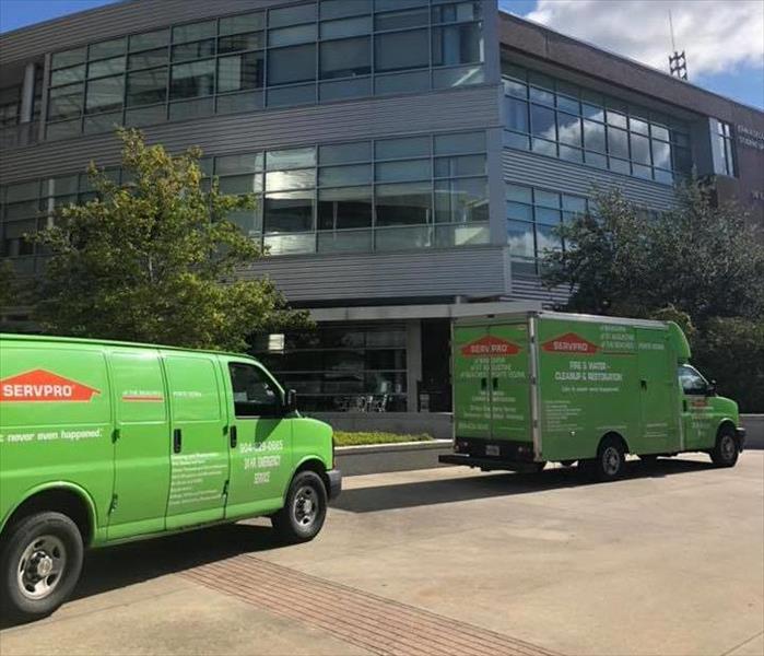 Image shows green vehicles parked in front of a college.