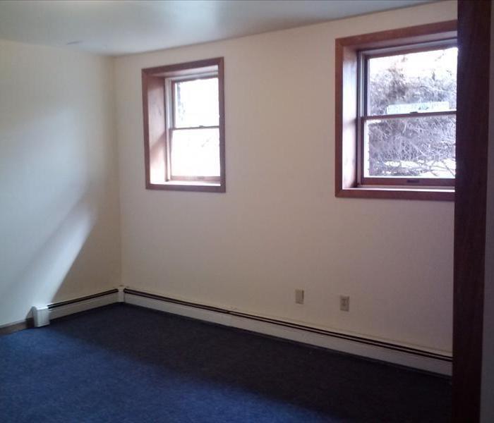 Images shows a room with 2 windows, fresh paint, and blue carpet.