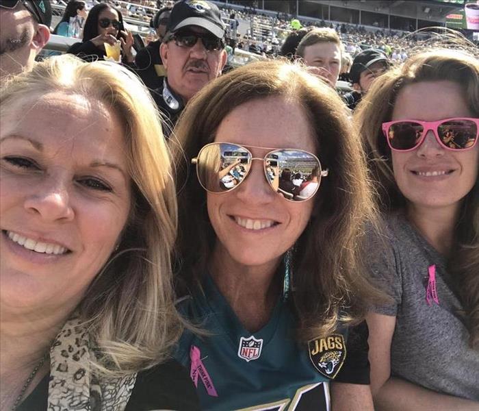 Image shows three ladies enjoying a football game in the stands.