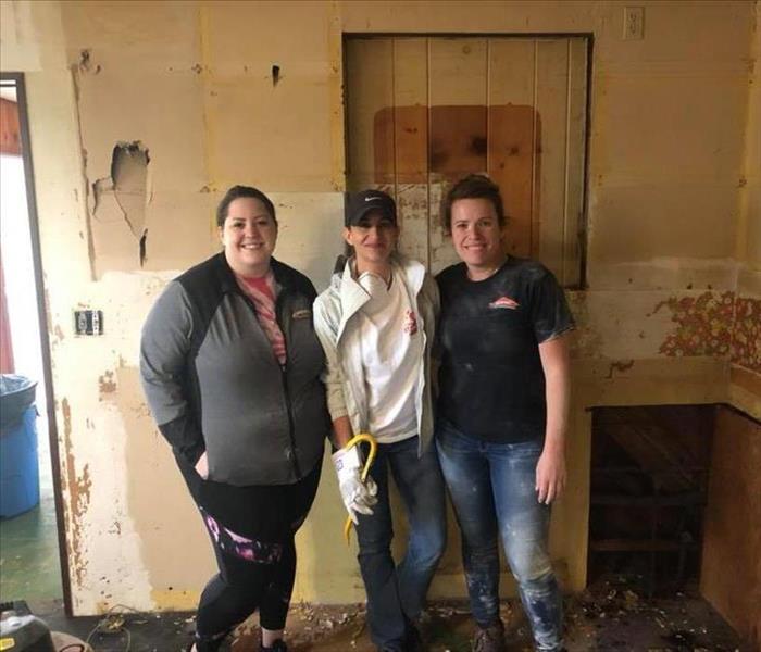 Image shows three ladies covered in dust working in a house.