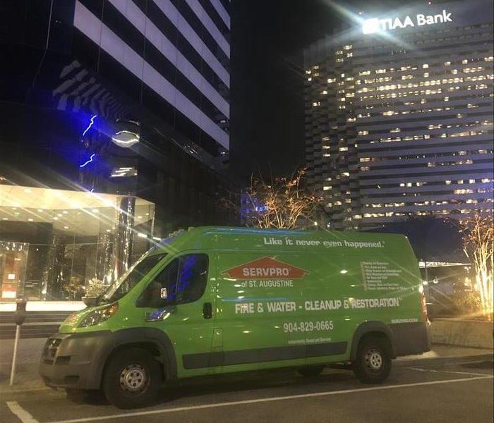 Image shows SERVPRO van on urban street at night with buildings and lights in the background.