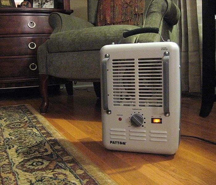 Image shows space heater sitting on the carpet in a home.