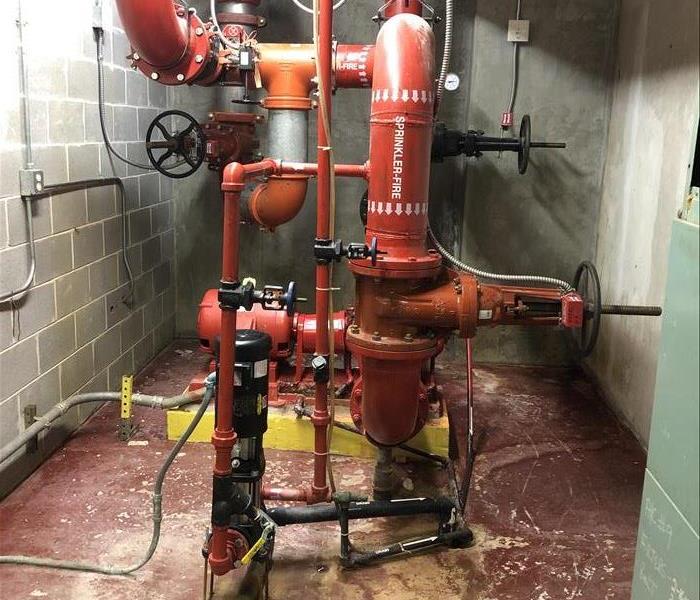 Image shows a fire suppression system's red pipes and main supply line and controls.